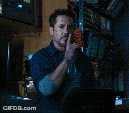 Robert Downey Jr. Is Sitting In A Chair With His Finger To His Lips . GIF