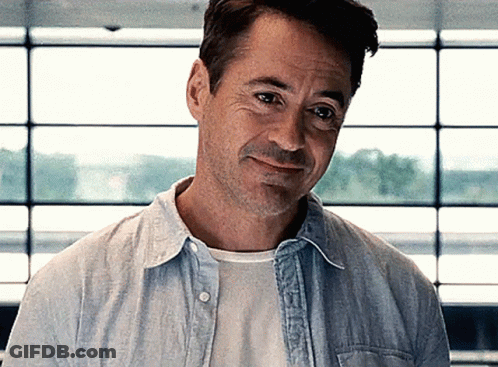 Robert Downey Jr. Is Wearing A Blue Shirt And White T-Shirt And Smiling . GIF