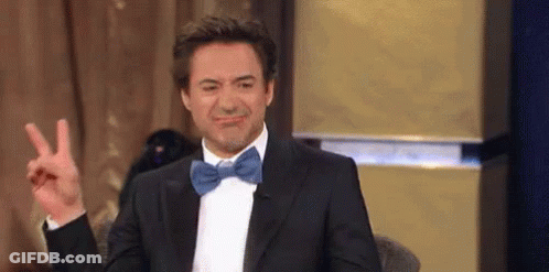 Robert Downey Jr. Is Wearing A Tuxedo And Bow Tie And Making A Peace Sign . GIF