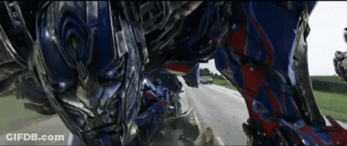 Robot Walking Down Road With Car Behind GIF