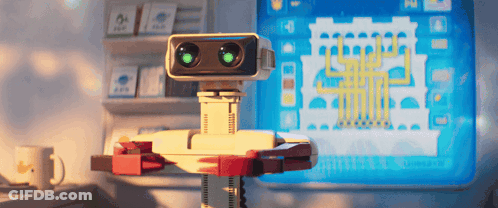 Robot With Green Eyes Sitting At Computer GIF