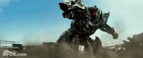 Robot With Gun Standing On Pile Of Cars GIF