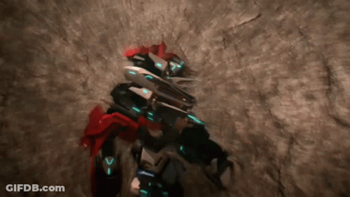 Robot With Letter V On Chest Standing In Cave GIF