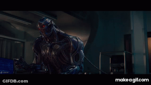 Robot With Red Eyes Sitting In Dark Room GIF