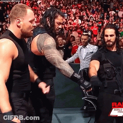 Roman Reigns And Seth Rollins Are Shaking Hands During A Wrestling Match . GIF