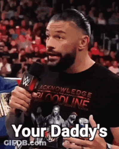 Roman Reigns Is Holding A Microphone And Saying `` Your Daddy 'S '' While Wearing A Black Shirt . GIF