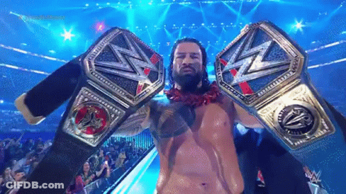 Roman Reigns Is Holding Two Wrestling Championship Belts In His Hands . GIF