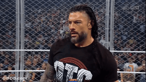 Roman Reigns Is Standing In A Wrestling Ring Wearing A T-Shirt That Says ' Tna ' . GIF
