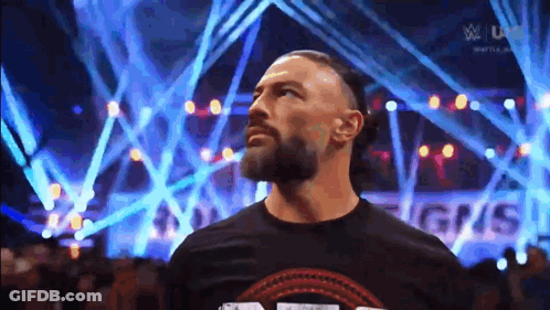 Roman Reigns Is Standing In Front Of A Crowd Of People In A Stadium . GIF