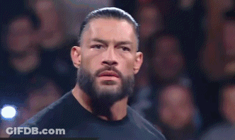 Roman Reigns Is Standing In Front Of A Crowd Wearing A Black Shirt . GIF