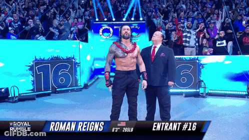 Roman Reigns Is Standing Next To A Man In A Suit In Front Of A Crowd GIF