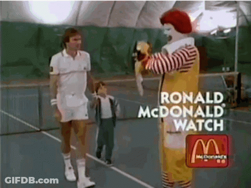 Ronald Mcdonald Is Standing On A Tennis Court With A Tennis Player GIF