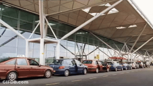 Row Of Cars Parked By Building With Taxi Sign GIF