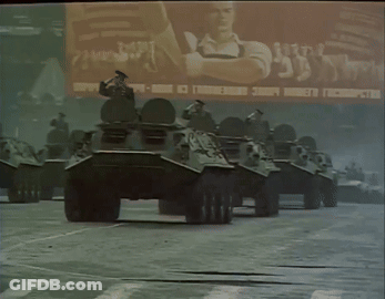 Row Of Military Vehicles In Front Of Russia Billboard GIF