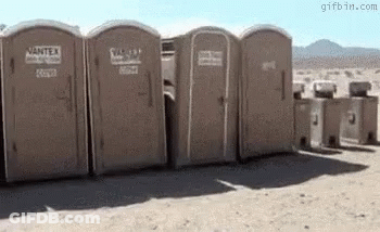 Row Of Portable Toilets In Desert GIF