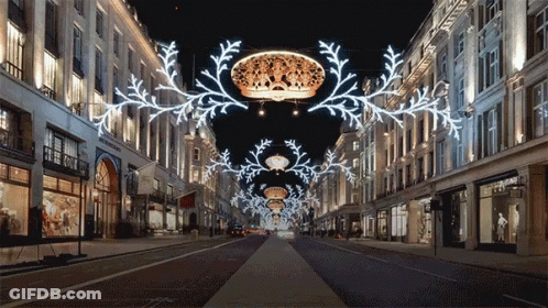 Row Of Shops Lit Up At Night With Crown Hanging GIF
