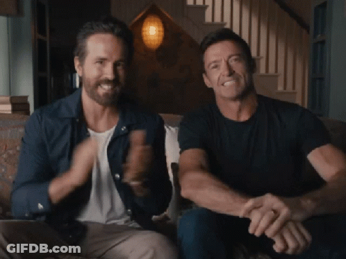 Ryan Reynolds And Hugh Jackman Are Sitting On A Couch And Smiling GIF