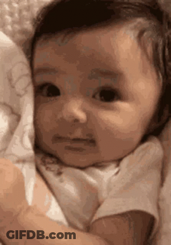 Sad Baby Lying In Blanket Looking At Camera GIF