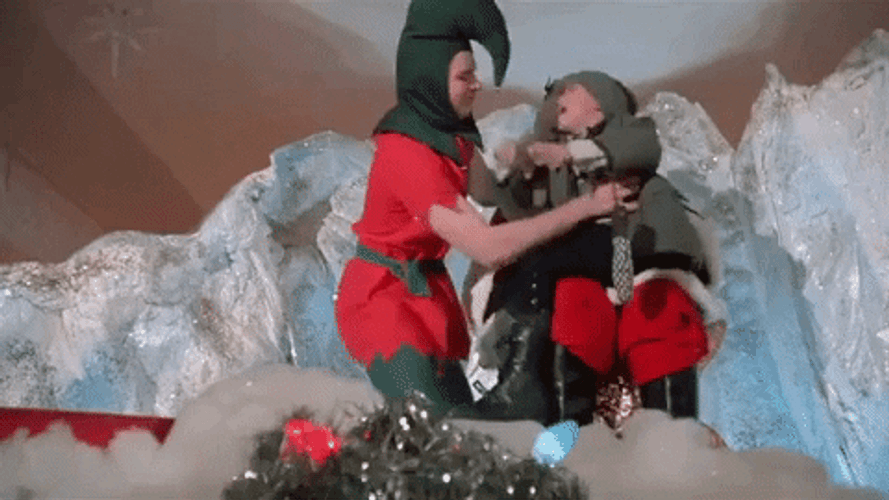 Santa Assistant Putting Kid On Slide GIF