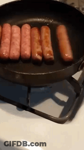 Sausages Are Cooking In A Frying Pan On A Stove Top GIF