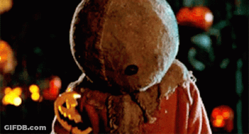 Scarecrow Holding Pumpkin In Front Of Pumpkins GIF