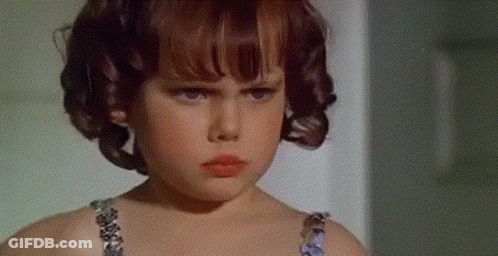 Serious Young Girl With Curly Hair Looking At Camera GIF