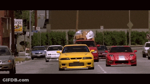 Several Cars Are Driving Down A Street In Front Of A Real Estate Sign GIF