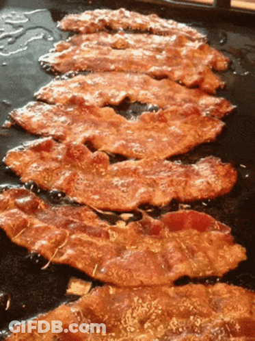 Several Slices Of Bacon Are Cooking On A Griddle GIF