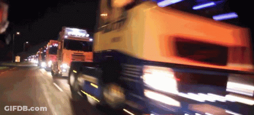Several Trucks Are Driving Down A Highway At Night And One Of Them Has The Word Scania On The Side GIF