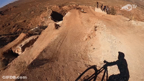 Shadow Of Person Riding Bike On Dirt Road With Red Bull TV Logo GIF