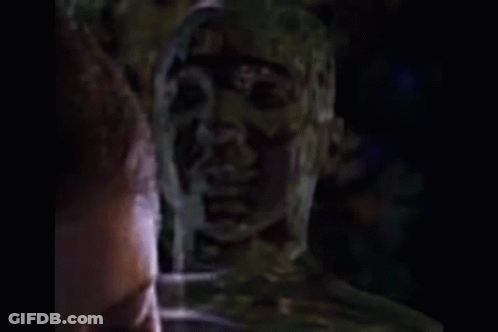 Shaved Head Man Talking To Another In Dark GIF