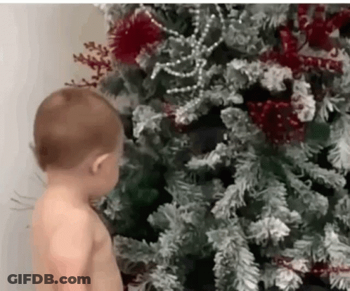 Shirtless Baby Next To Christmas Tree GIF