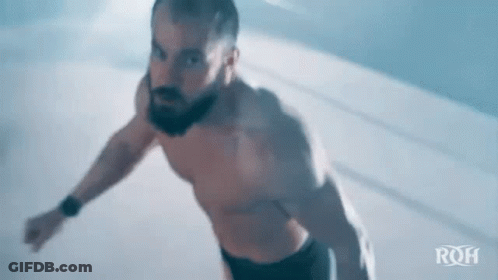 Shirtless Bearded Man Jumping In Dark Room GIF