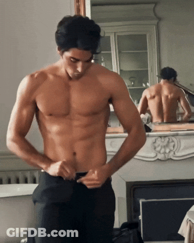 Shirtless Man Adjusting Pants By Fireplace GIF