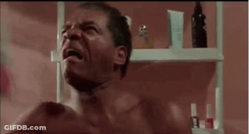 Shirtless Man Crying In Bathroom Next To Perfume Shelf GIF