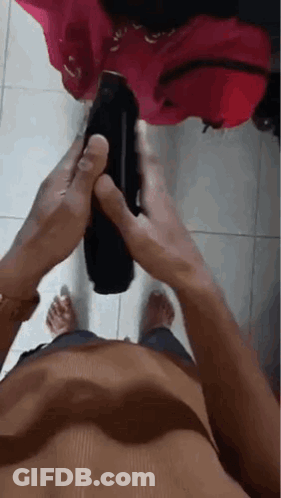 Shirtless Man Holding Black Object On Tiled Floor GIF