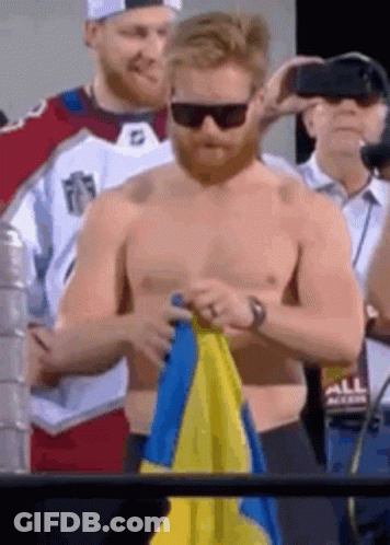 Shirtless Man Holding Blue And Yellow Flag GIF