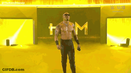 Shirtless Man Holding Microphone By Yellow Wall GIF