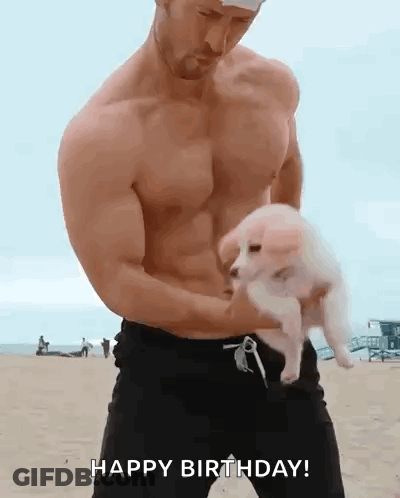 Shirtless Man Holding Puppy On Beach Saying Happy Birthday GIF