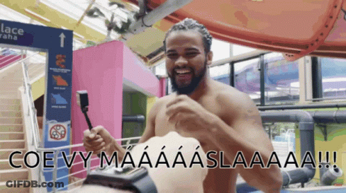 Shirtless Man Holding Remote In Front Of Lace Sign GIF