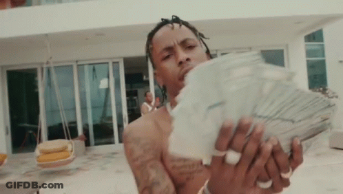 Shirtless Man Holding Stack Of Money In Front Of Large House GIF