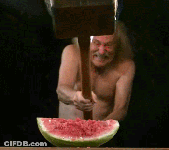 Shirtless Man Holding Wooden Hammer Over Watermelon GIF