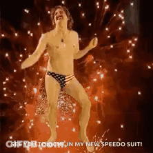 Shirtless Man In American Flag Swim Trunks Dancing In Front Of Fireworks GIF