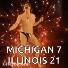 Shirtless Man In Bathing Suit Dancing In Front Of Fireworks GIF