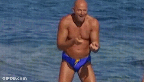 Shirtless Man In Blue Swim Trunks Jumping Into Ocean GIF