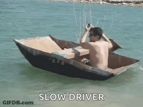 Shirtless Man In Cardboard Boat Saying Slow Driver GIF