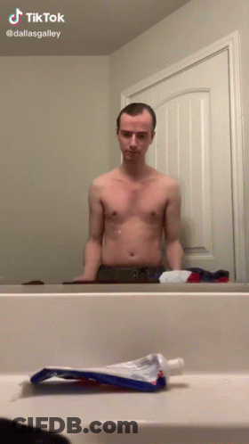 Shirtless Man In Front Of Bathroom Mirror With Toothpaste GIF