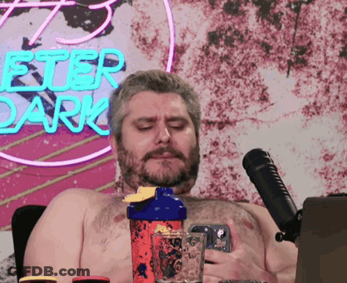Shirtless Man In Front Of Peter Dark Neon Sign GIF