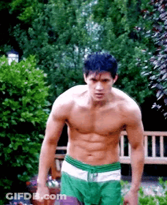 Shirtless Man In Green Shorts Standing In Garden GIF