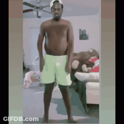 Shirtless Man In Green Shorts Standing In Living Room GIF